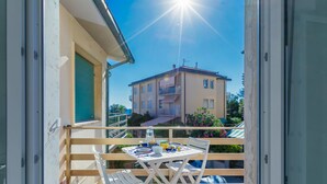 A balcony with a table and chairs, overlooking a building with multiple balconies and a clear sky. - Casa Emma by Interhome (Cecina)