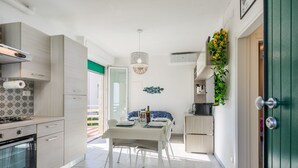 A modern kitchen with a dining area, a green door, and a view of the outdoors. - Casa Emma by Interhome (Cecina)