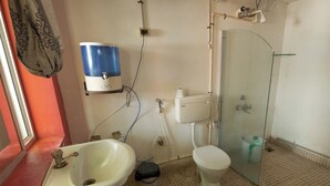 A bathroom with a white sink, toilet, and glass shower enclosure. - Sunshine Guest House (Tiruvannamalai)