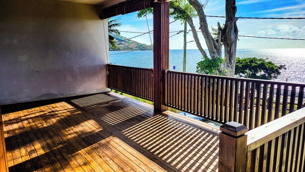 A wooden deck with a view of the sea and palm trees. - Charming 2-bedroom villa with WiFi, AC in pleasant Vieux Grand Port (Vieux Grand Port)