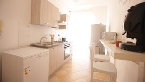 A kitchen with a dishwasher, oven, and a white countertop with a coffee machine. - Relax in an apartment in the city center (Palermo)