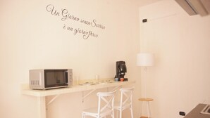 A small kitchenette with a microwave, coffee maker, and bar stools. - Relax in an apartment in the city center (Palermo)