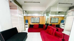 A living room with a black and red sofa, a flat-screen TV mounted on the wall, and a water dispenser. - Cosmo Hotel (Quezon City)