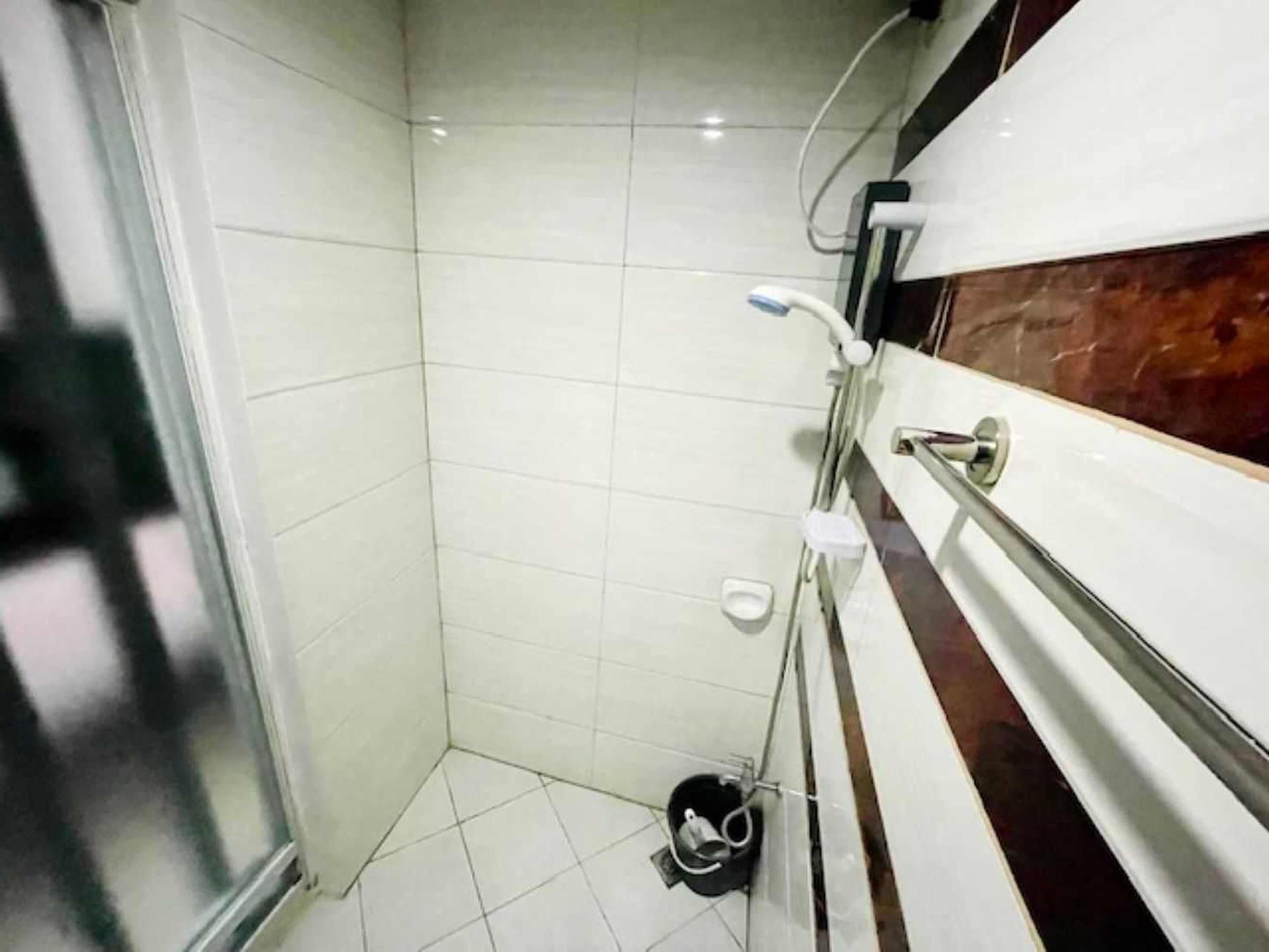 A small, tiled bathroom with a shower, a toilet, and a hand basin.
