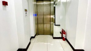 A clean, modern elevator in a hallway with white walls and a tiled floor. - Cosmo Hotel (Quezon City)