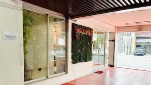 A hotel lobby with a red carpet, a glass wall with a decorative plant, and a sign on the wall. - Cosmo Hotel (Quezon City)