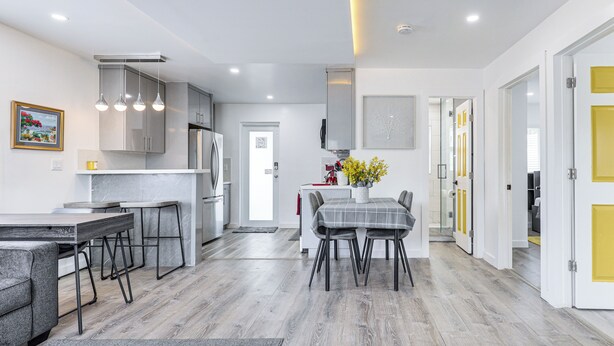 Una cocina moderna con armarios grises, un comedor con mantel a cuadros y un sofá gris.