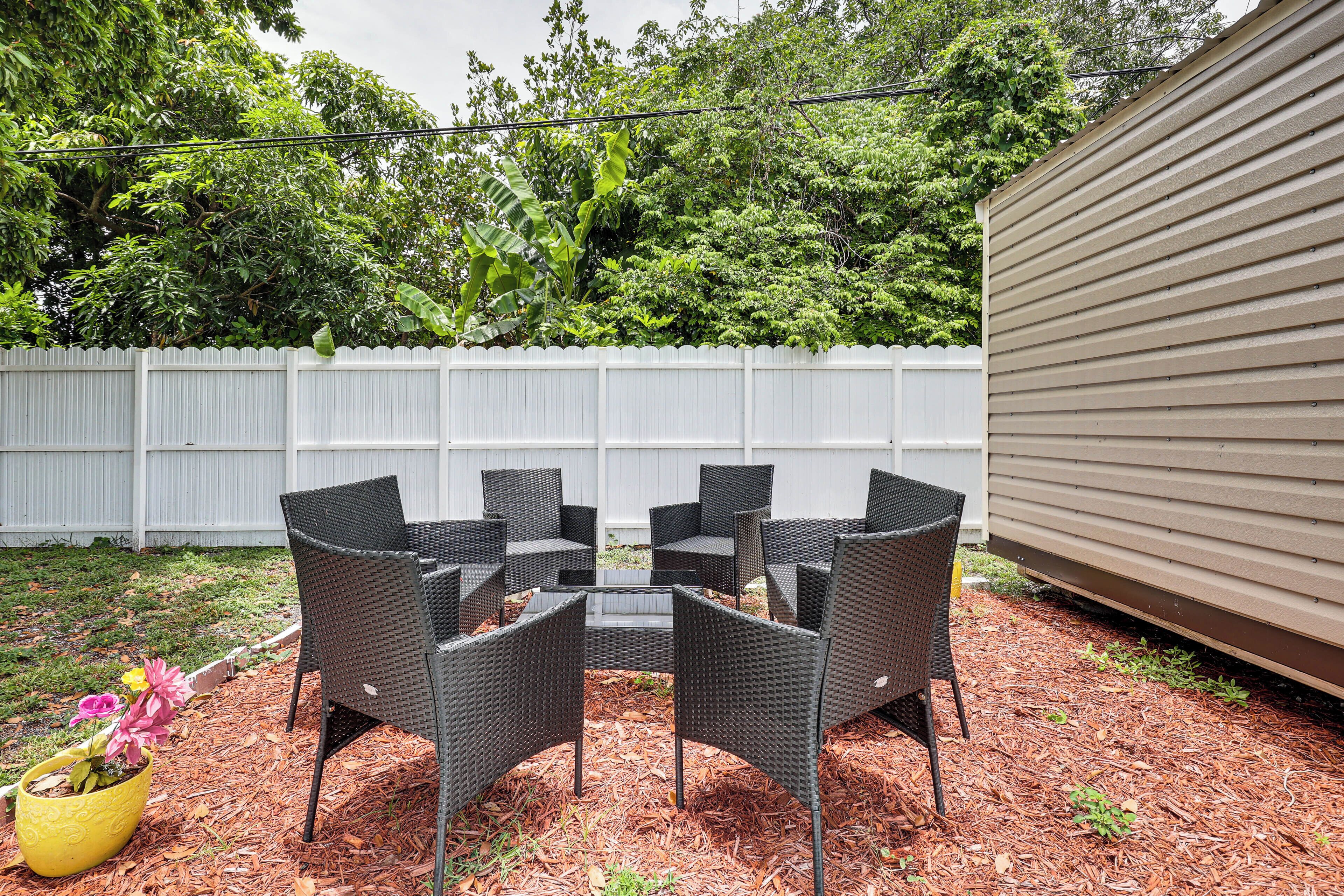 A patio area with a white fence, a pergola, and a table with chairs.