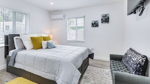 Un dormitorio moderno con cama, mesitas de noche, un sofá y obras de arte en las paredes.