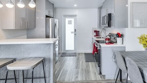 Una cocina moderna con gabinetes grises, electrodomésticos de acero inoxidable y una zona de bar con taburetes.