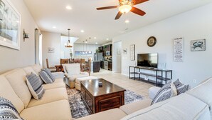 A spacious living room with a large sofa set, a coffee table, and a television. - Pool & Lazy River: Windsor House 9 Mi to Disney! (Kissimmee)