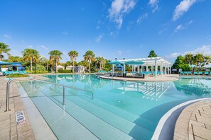 Piscina cristalina com espreguiçadeiras e guarda-sóis, cercada por palmeiras e um gazebo.
