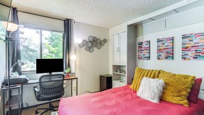 A bedroom with a bed, desk, computer, and a window. - Walk to Virginia Lake: Reno Condo w/ Balcony! (Reno)