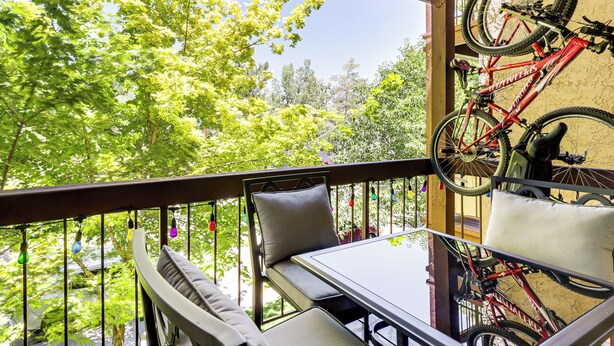 A balcony with a table and chairs, a bicycle mounted on the wall, and a view of trees. - Walk to Virginia Lake: Reno Condo w/ Balcony! (Reno)