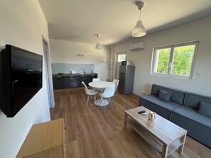 A compact living space with a kitchenette, a dining area, and a seating area with a sofa and a coffee table. - Apartment 2025 RDC air-conditioned (Brézins)