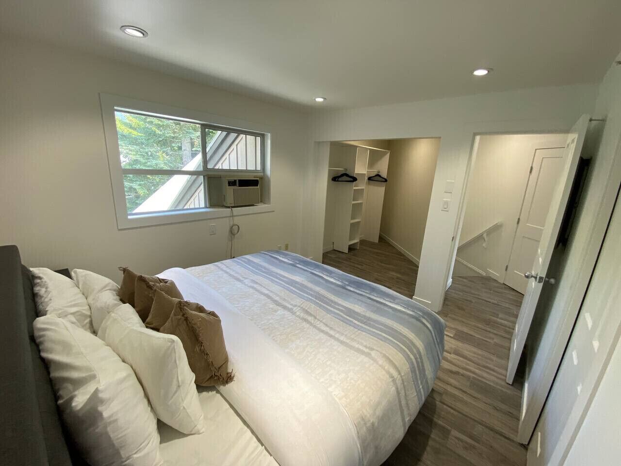 Camera da letto con un letto grande, una finestra, un armadio a muro e una porta che conduce a un'altra stanza.