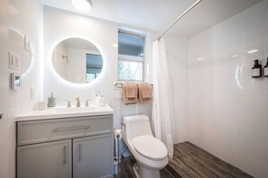 Un baño moderno con tocador blanco, inodoro y zona de ducha.
