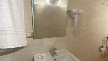 Un baño con lavamanos blanco, un bidé, un espejo y un secador de pelo.