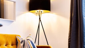 A modern living room with a yellow sofa, a black floor lamp, and a mirror on the wall. - Hilltown by Central Serviced Apartments (Dundee)