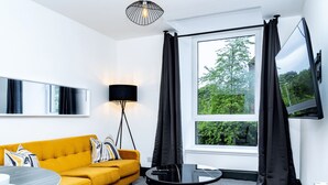 A modern living room with a yellow sofa, a black coffee table, a floor lamp, and a large window with curtains. - Hilltown by Central Serviced Apartments (Dundee)