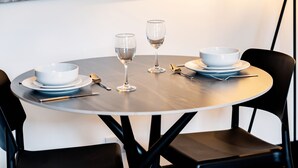 A round dining table with two white bowls, two wine glasses, and cutlery. - Hilltown by Central Serviced Apartments (Dundee)