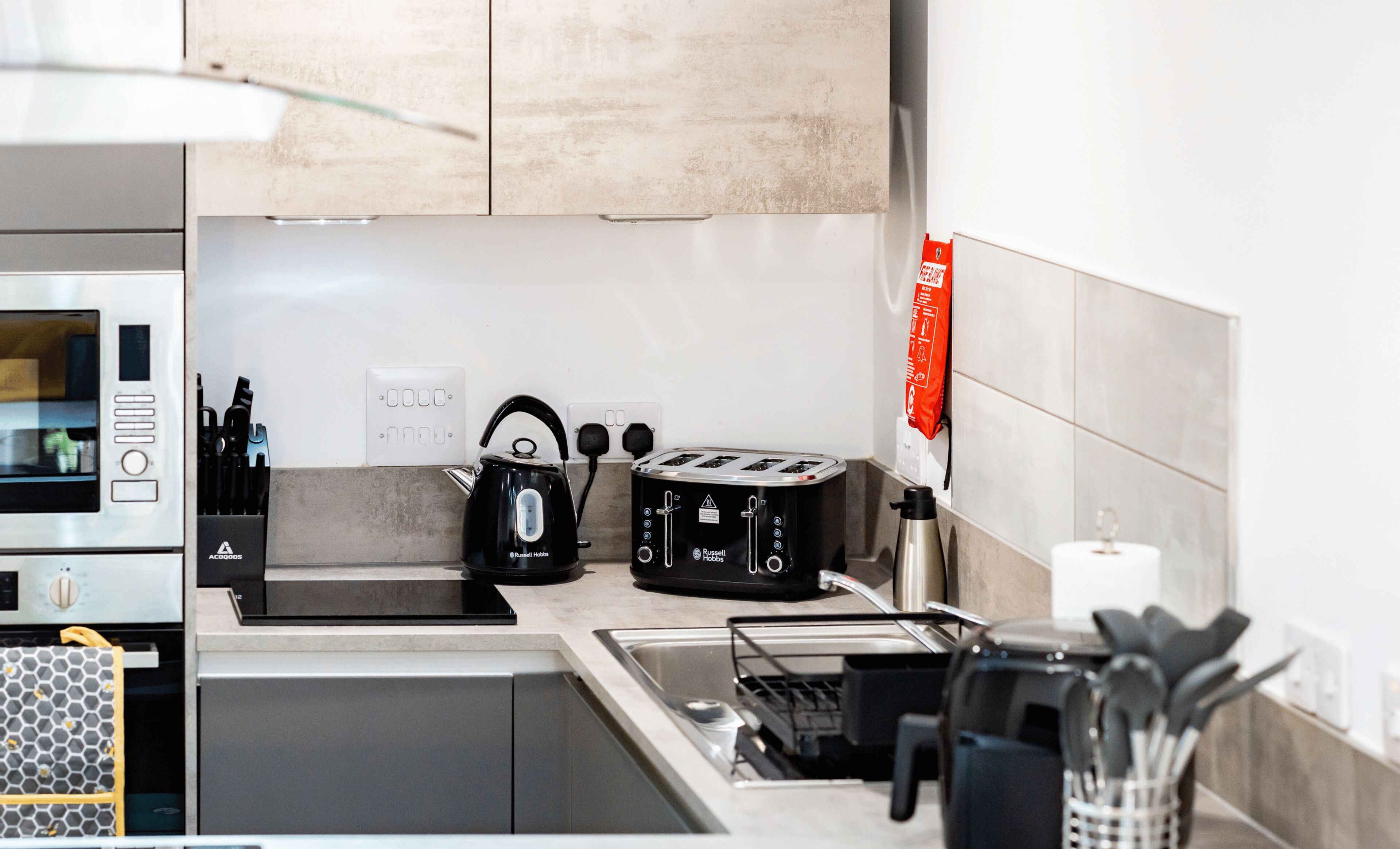 Una cucina moderna con forno a incasso, bollitore, tostapane e lavello.