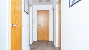 Um corredor com portas de madeira, paredes brancas e chão claro.