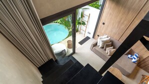 A modern interior with a staircase leading to a balcony overlooking a swimming pool. - Exhale Villa by Betterplace (Canggu)