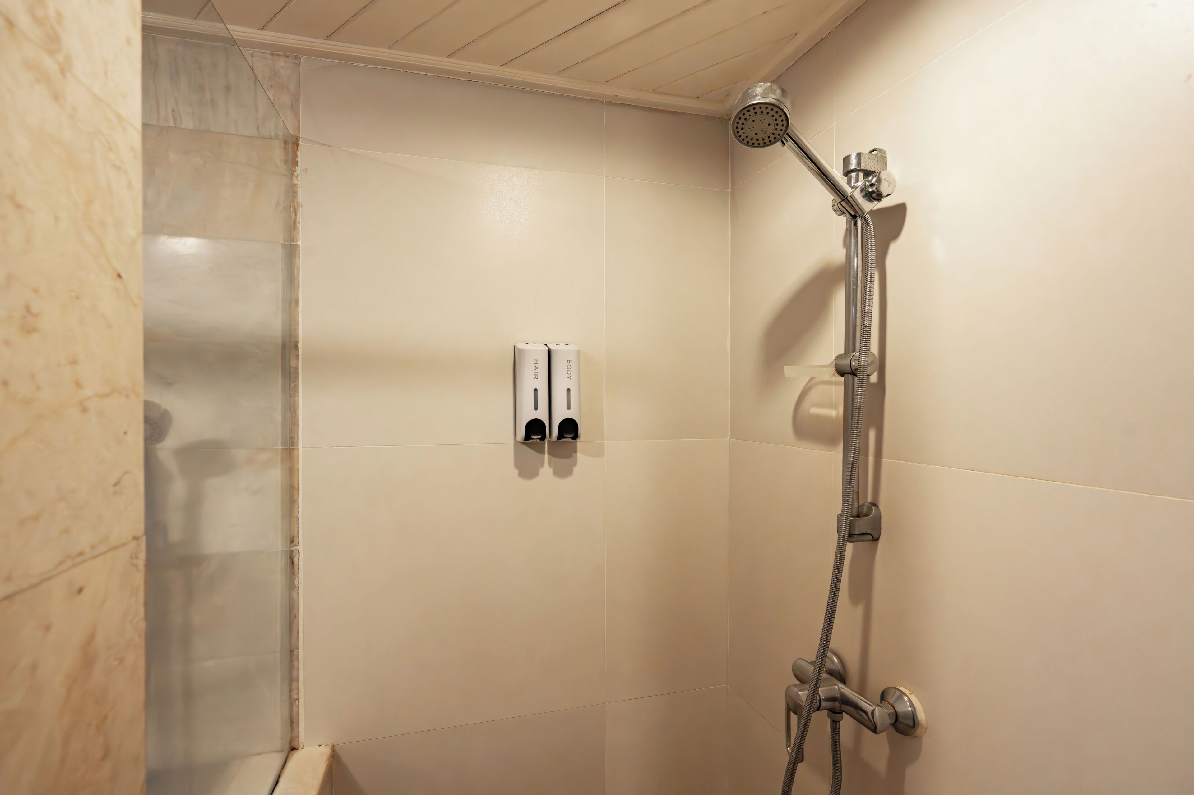 A shower with a handheld showerhead and a wall-mounted faucet.