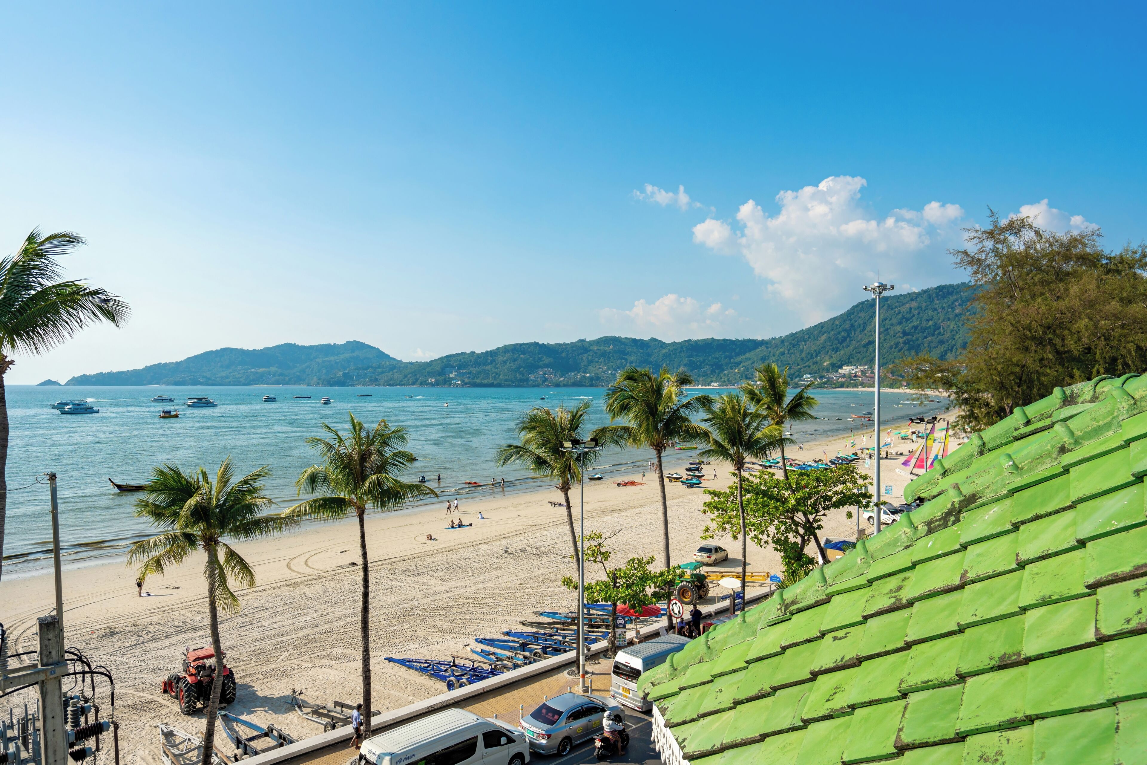 A beach with boats, palm trees, and a clear sky.