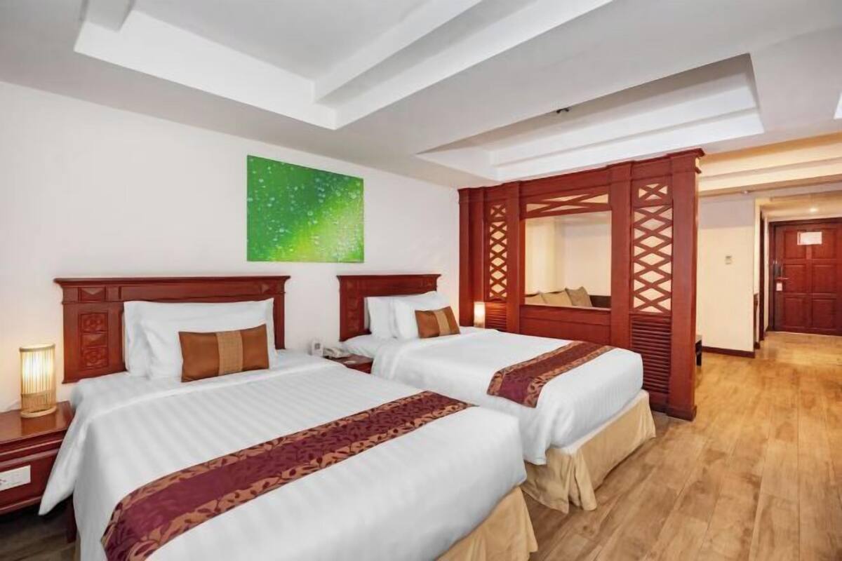 Habitación de hotel con dos camas, un ventanal grande, una obra de arte verde en la pared y un panel de madera.