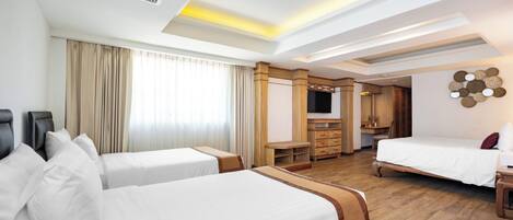 A hotel room with two beds, a TV, a wooden cabinet, and a ceiling with skylights.