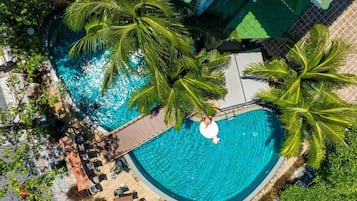 An aerial view of a circular swimming pool surrounded by palm trees and lounge chairs.