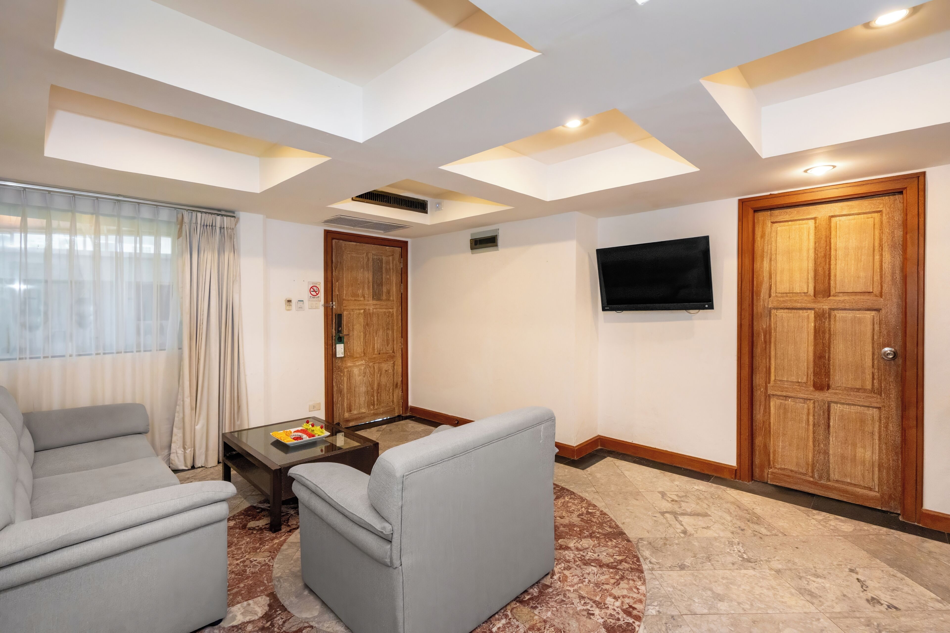 A modern living room with a sofa, a coffee table, a TV, and a wooden door.