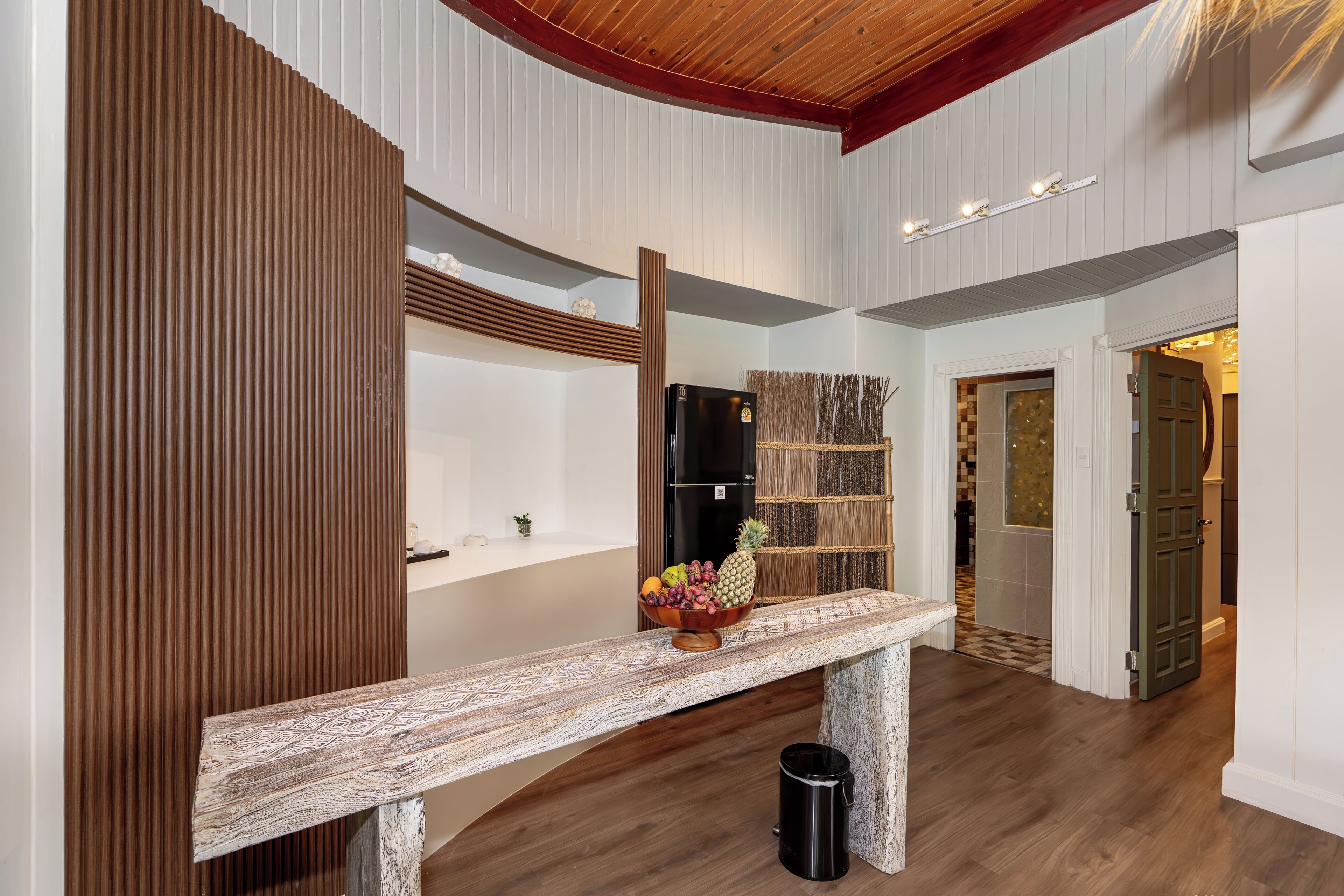 A modern interior with a wooden bench, a fruit bowl, and a mirror.