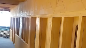 A row of wooden-paneled rooms with a single chair in the foreground. - Green Land Guest House (Taobat)