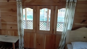 A wooden cabin room with two beds, a small table, and a window with a lattice design. - Green Land Guest House (Taobat)