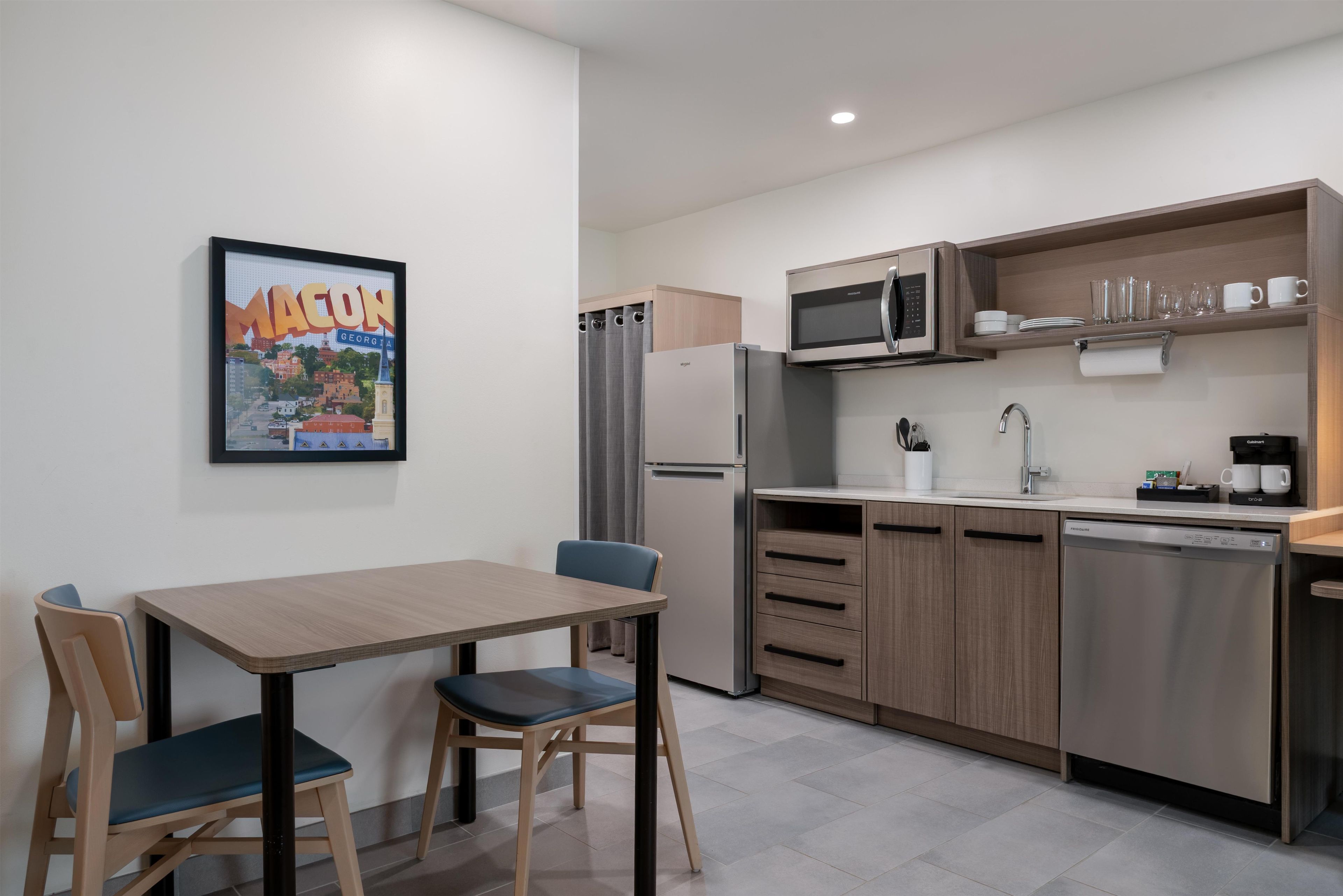 A modern kitchen with a dining table and chairs, a refrigerator, microwave, and a dishwasher.