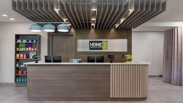 A modern hotel reception desk with a digital display, a self-service kiosk, and a vending machine.
