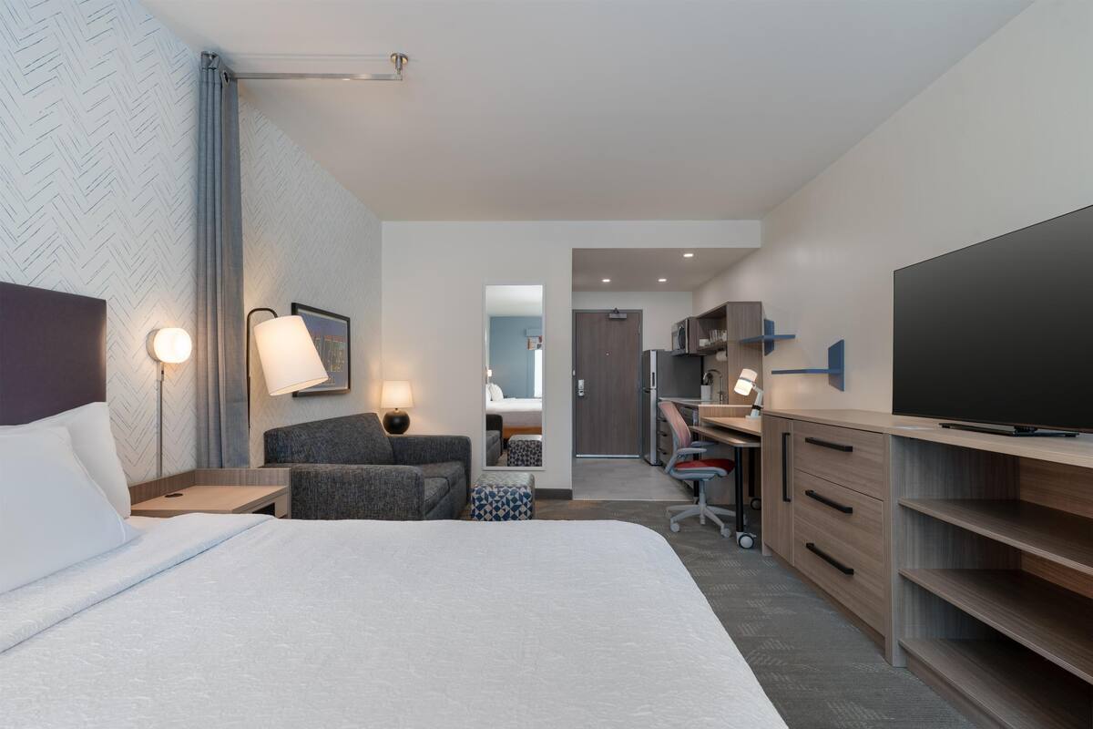 Une chambre d’hôtel équipée d’un lit, d’un bureau, d’une télévision et d’une kitchenette.