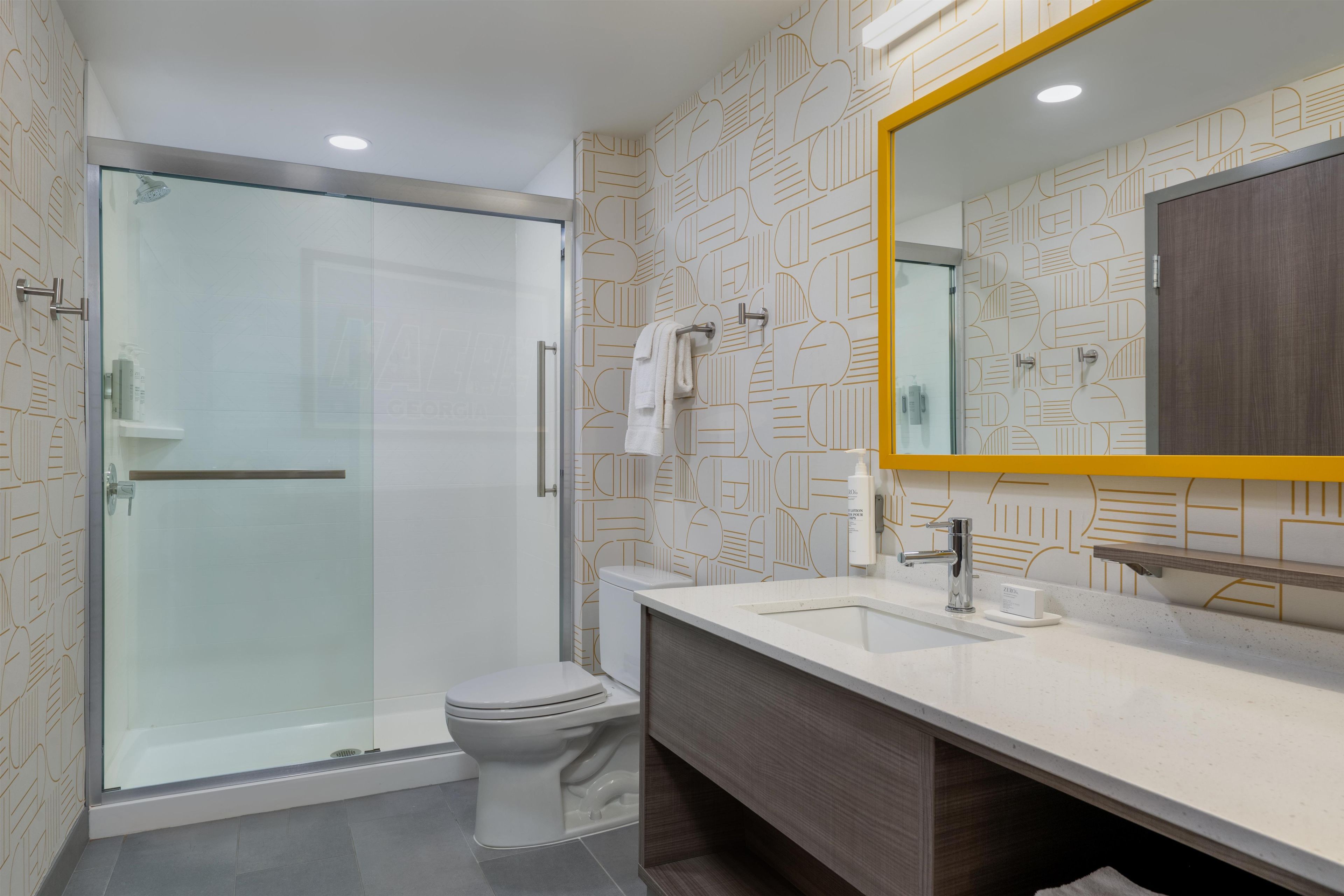A modern bathroom with a glass shower enclosure, a white toilet, and a vanity with a mirror.