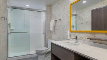 A modern bathroom with a glass shower enclosure, a white toilet, and a vanity with a mirror.