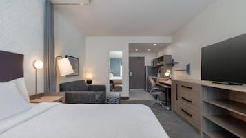 A hotel room with a bed, a desk, a chair, a television, and a mirror.