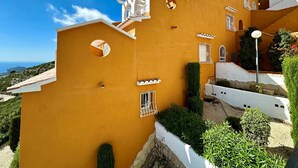 A multi-story building with a yellow facade, white balconies, and circular windows.