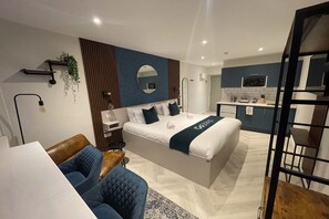 A modern hotel room with a bed, a desk, a chair, a small table, a microwave, and a sink. - stays | Superior Double Studio (Middlesbrough)