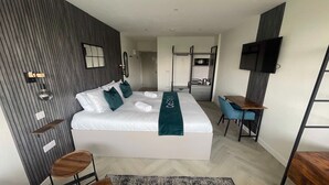 Ein modernes Hotelzimmer mit einem großen Bett, einem Schreibtisch, einem Fernseher und einem Kleiderschrank.