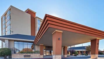 A hotel with a covered entrance, large windows, and a stone facade.