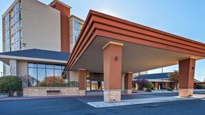 Un hotel con vestíbulo cubierto, amplias ventanas y fachada de piedra.