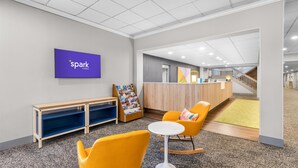Un moderno vestíbulo de hotel con mostrador de recepción, zona de estar y área de juegos para niños.