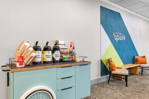 A coffee station with various beverages and a wall with a geometric design and the text 'It only takes a spark.' - Spark by Hilton Lockport (Lockport)